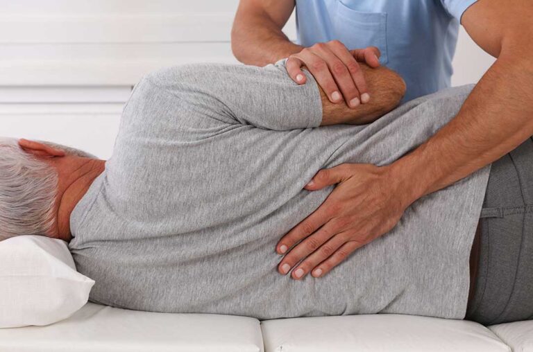 An older adult practicing gentle stretching with assistance in a cozy living room.