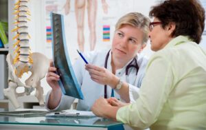 Patient discusses a back pain treatment plan with a chiropractor in a bright examination room.