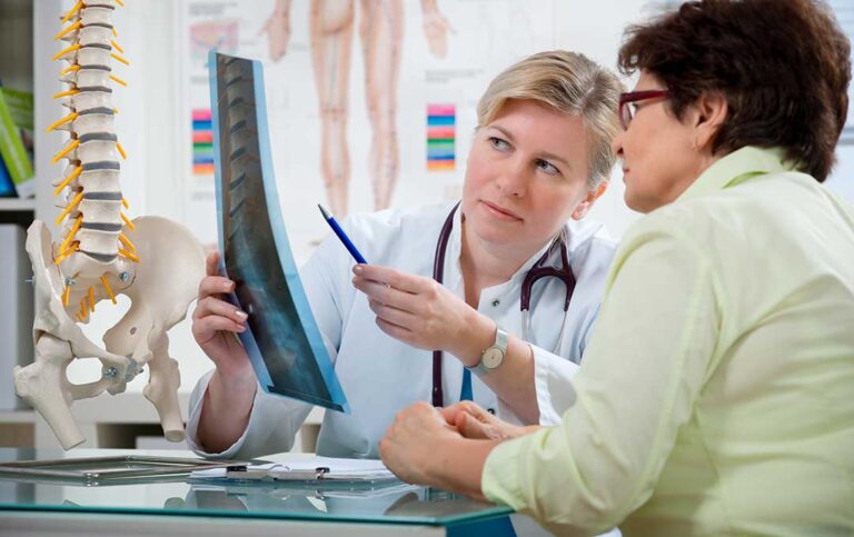 Patient discusses a back pain treatment plan with a chiropractor in a bright examination room.